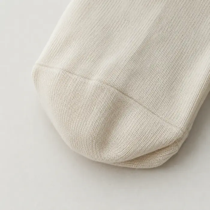 Extreme close-up of the toe seam of a folded cream cotton lisle sock.