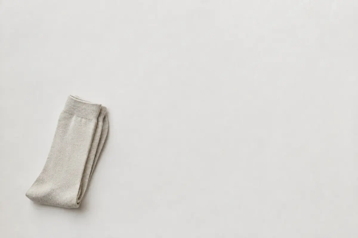A single folded pair of pale stone socks at the lower left of a very large empty sheet of chalk paper.