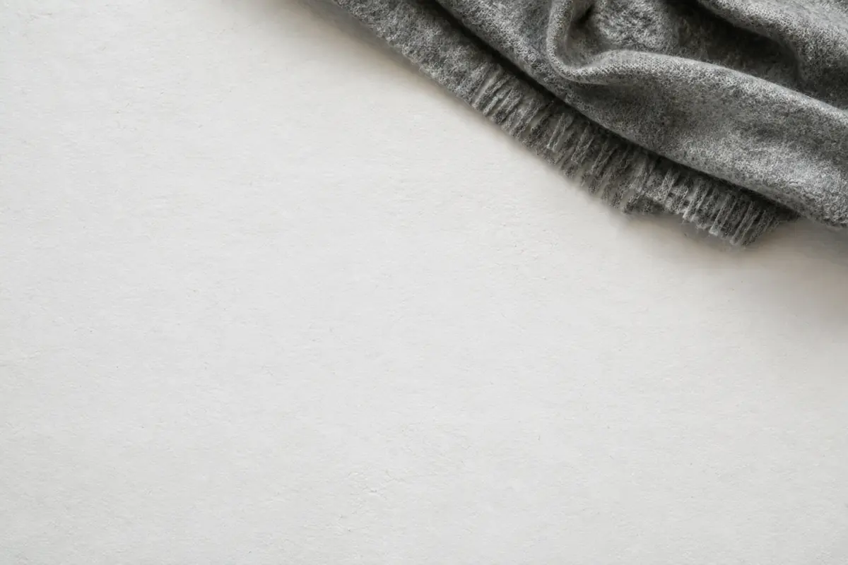 A folded grey wool blanket corner in the top corner of an otherwise empty chalk paper frame.
