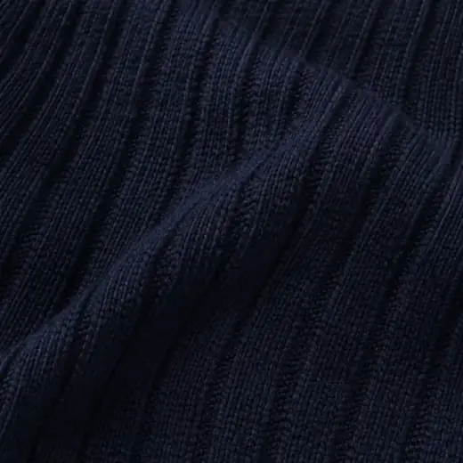 Extreme close-up of navy ribbed merino sock knit, raking light showing the rib channels.