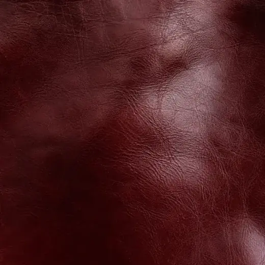Extreme close-up of an oxblood polished leather surface with fine creasing.